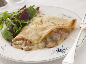 Royalty Free Photo of a Savoury Pancake Filled With Ham Cheese and Mushrooms With Dressed Salad