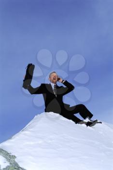 Royalty Free Photo of a Man Talking on a Cellphone Sitting on the Mountain