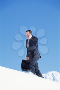 Royalty Free Photo of a Man Walking on a Snowy Mountain Talking on a Cellphone