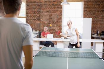Royalty Free Photo of a Man and Woman Playing Ping Pong in an Office