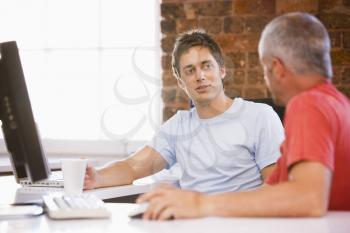 Royalty Free Photo of Two Men Talking by a Computer