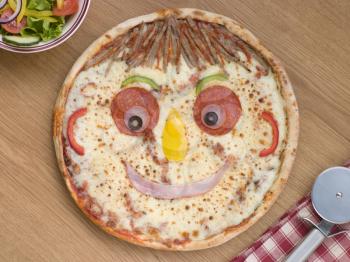 Royalty Free Photo of a Smiley Faced Pizza With a Side Salad