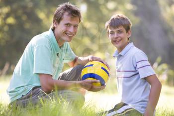Royalty Free Photo of a Young Man and Boy With a Soccer Ball