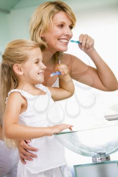 Royalty Free Photo of a Woman and Girl Brushing Their Teeth