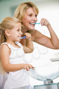 Royalty Free Photo of a Woman and Daughter Brushing Their Teeth