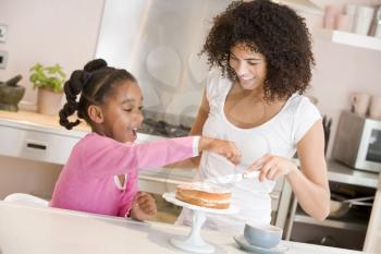 Royalty Free Photo of a Woman and Daughter Icing a Cake