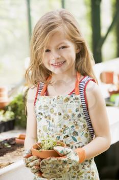 Royalty Free Photo of a Child in a Greenhouse With a Potted Plant