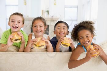 Royalty Free Photo of Four Children Eating Cheeseburgers in a Living Room