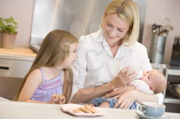 Royalty Free Photo of a Mother Feeding a Baby With Her Daughter Beside Her