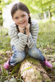 Royalty Free Photo of a Young Girl Sitting on a Log