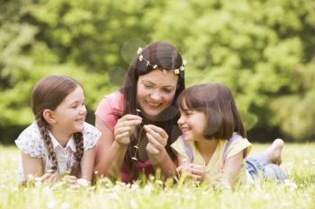 Royalty Free Photo of a Mother and Daughters Making Flower Chains