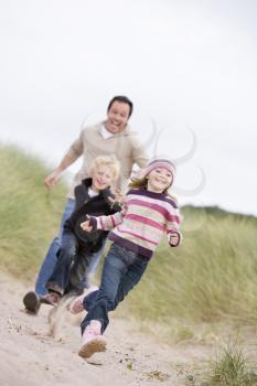 Royalty Free Photo of a Father and Two Children Running at the Beach