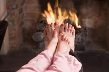 Royalty Free Photo of a Mother and Daughter Warming Their Feet at a Fire