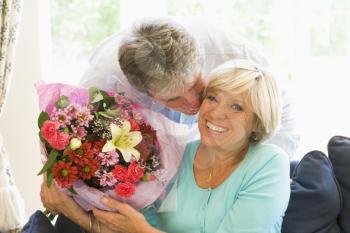 Royalty Free Photo of a Man Giving His Wife Flowers and Kissing Her Cheek
