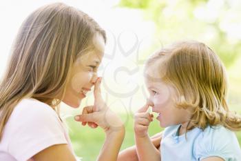 Royalty Free Photo of Two Sisters Pointing at Their Noses