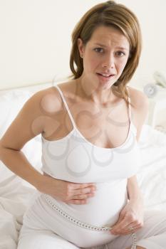 Royalty Free Photo of a Pregnant Woman Measuring Her Belly and Looking Nervous