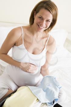Royalty Free Photo of a Pregnant Woman Packing Baby Clothes