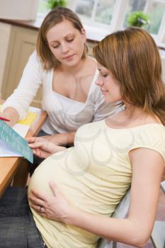 Royalty Free Photo of a Pregnant Woman Reading a Pamphlet With a Friend