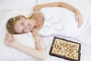 Royalty Free Photo of a Pregnant Woman in Bed Eating Chocolate