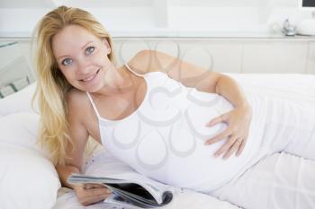 Royalty Free Photo of a Pregnant Woman Reading in Bed