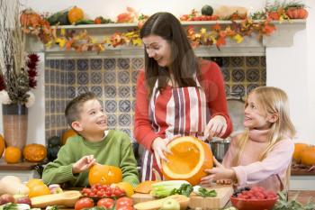 Royalty Free Photo of a Mother and Children Carving a Pumpkin