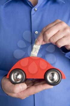 Royalty Free Photo of a Person Putting Money in a Car Bank