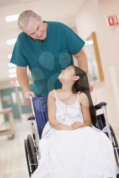 Royalty Free Photo of an Orderly Pushing a Little Girl in a Wheelchair
