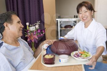 Royalty Free Photo of a Nurse Serving a Patient His Food