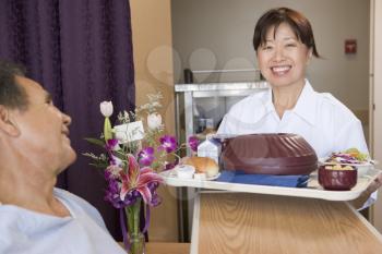 Royalty Free Photo of a Nurse Serving a Meal to a Patient