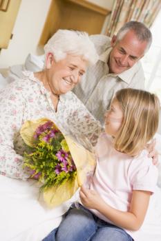 Royalty Free Photo of a Granddaughter Giving Her Grandma Flowers in the Hospital