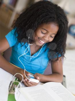 Royalty Free Photo of a Young Girl With Homework Listening to an MP3 Player