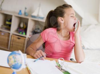 Royalty Free Photo of a Girl Doing Homework and Yawning