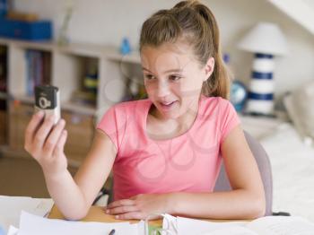 Royalty Free Photo of a Girl Distracted From Her Homework Playing With Her Cellphone