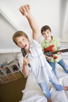 Royalty Free Photo of a Boy Playing Guitar and Another Boy Singing Into a Hairbrush