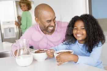 Royalty Free Photo of a Father and Daughter Having Breakfast With the Mother Behind Them