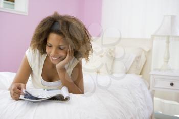 Royalty Free Photo of a Girl Reading on Her Bed