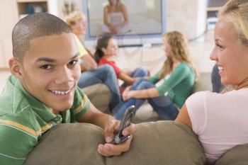 Royalty Free Photo of Teens Watching TV and a Boy Using a Cellphone