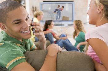 Royalty Free Photo of Teens Watching TV and a Boy Talking on the Cellphone