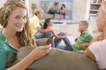 Royalty Free Photo of Teens Watching TV and a Girl on a Cellphone