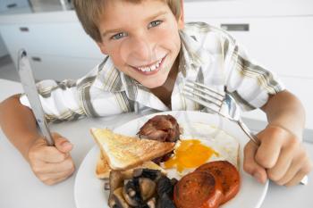 Royalty Free Photo of a Boy Eating Bacon and Eggs