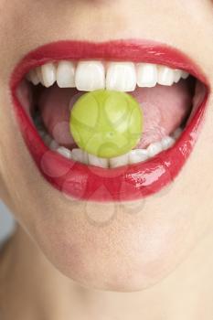 Royalty Free Photo of a Mouth Holding a Grape