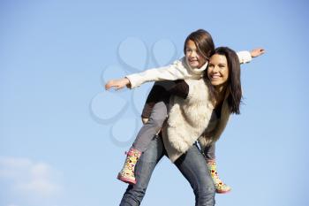 Royalty Free Photo of a Mother Giving Her Daughter a Piggyback Ride