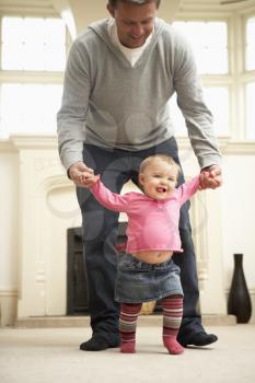 Royalty Free Photo of a Father Helping His Daughter Walk