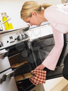 Royalty Free Photo of a Woman Taking Cookies Out of the Oven