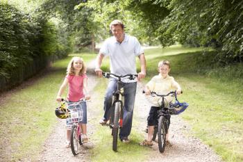 Royalty Free Photo of a Father and His Children Riding Bikes