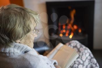 Royalty Free Photo of a Woman Reading by a Fire