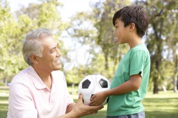 Grandfather And grandson In Park With Football