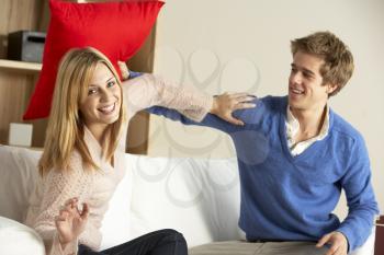 Young Couple Having Play Fight On Sofa