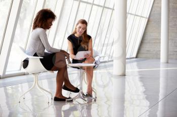 Two Businesswomen Meeting In Reception Of Modern Office