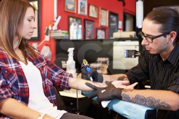 Woman Sitting In Chair Having Tattoo On Arm In Parlor